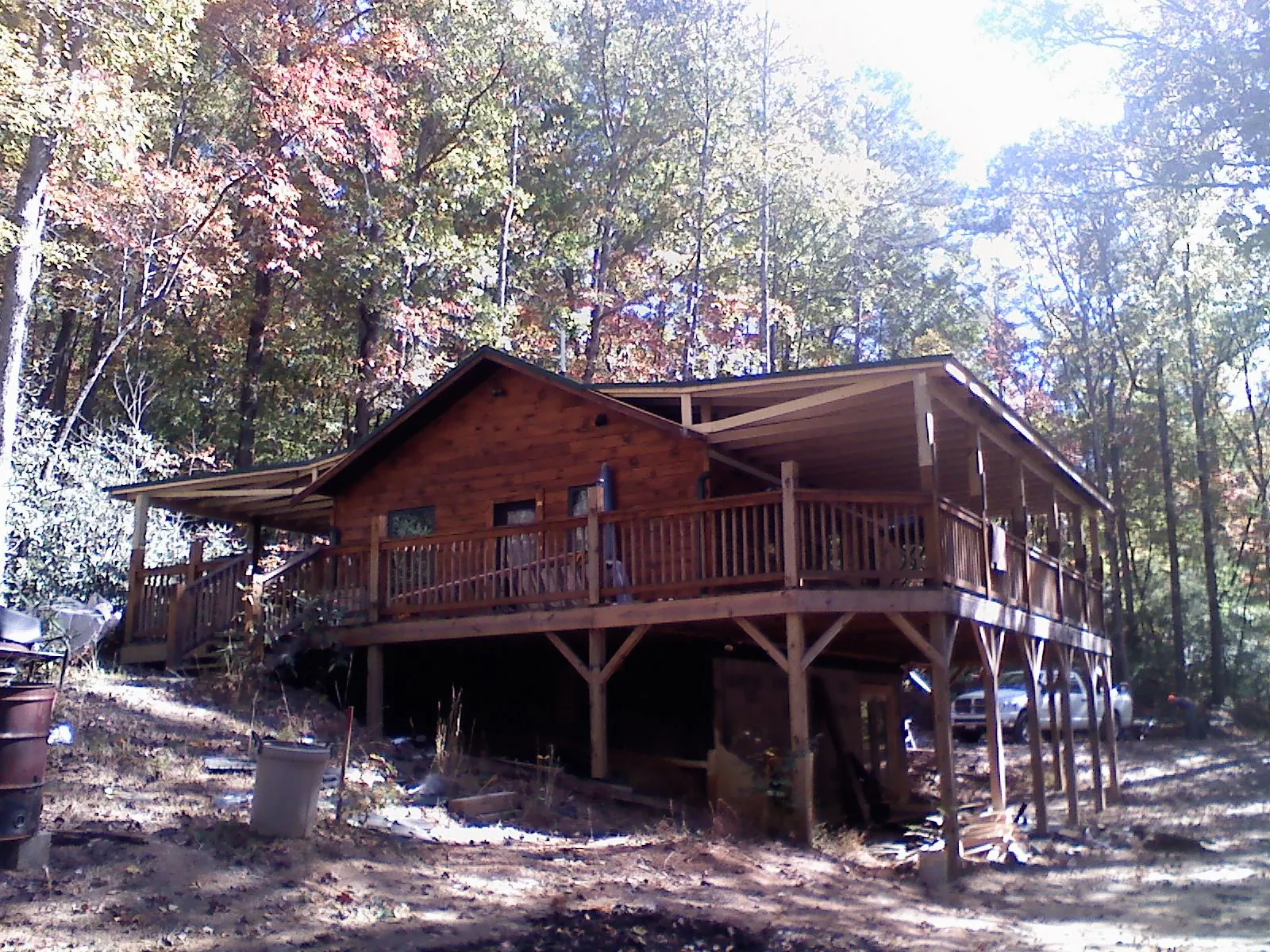 Log cabin with a wraparound porch and metal roof in the fall in Coral