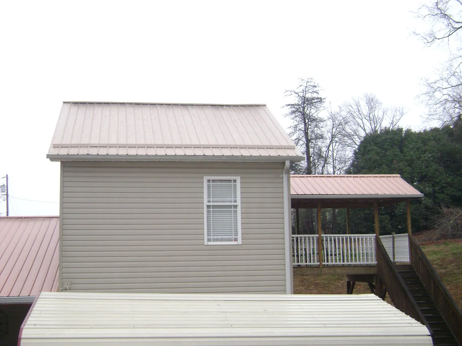 Tan metal roofs on a two story addition and attached porch, from a Roof Replacement job in Coral